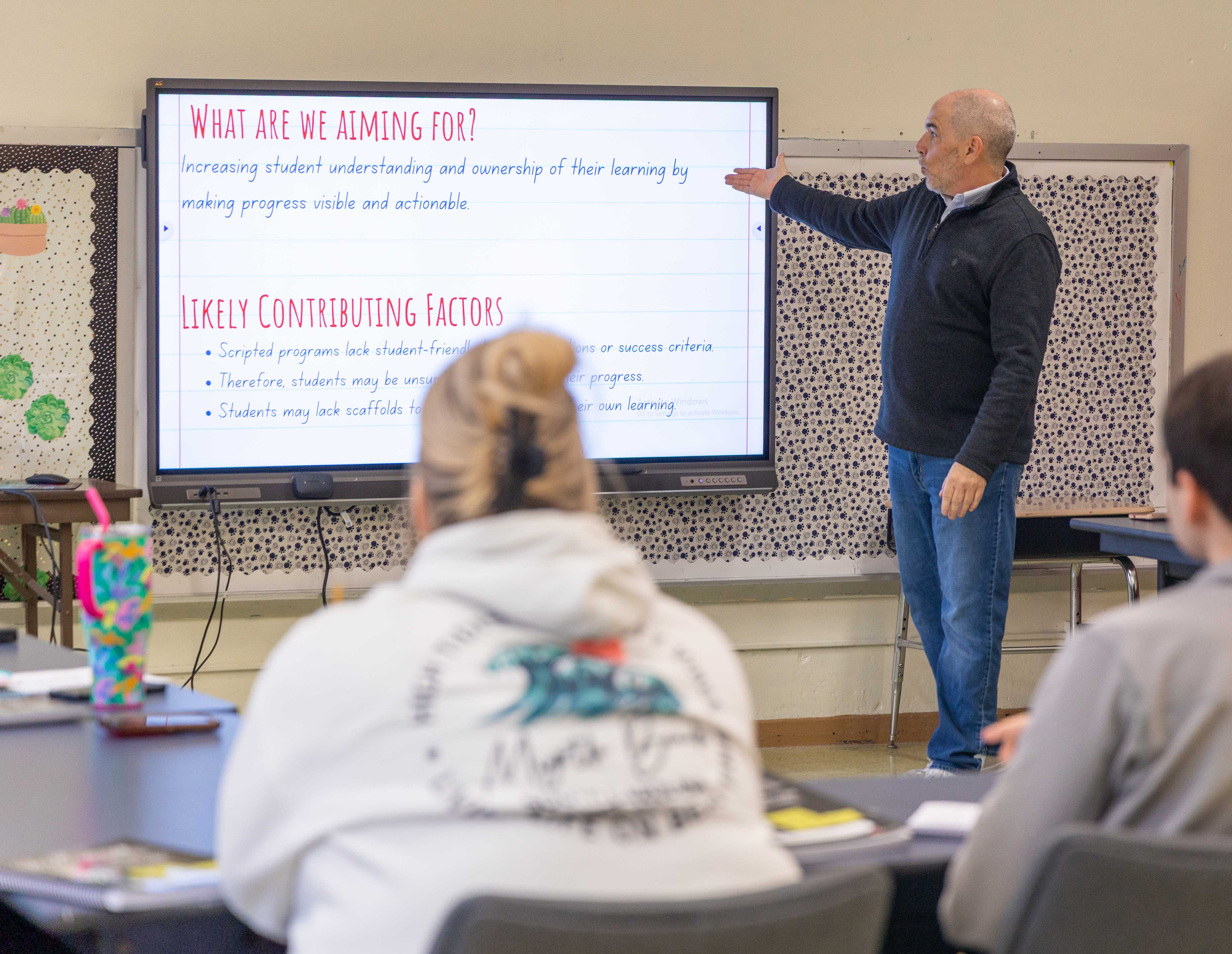 Scott McDonald points to a screen about contributing factors to a classroom of faculty